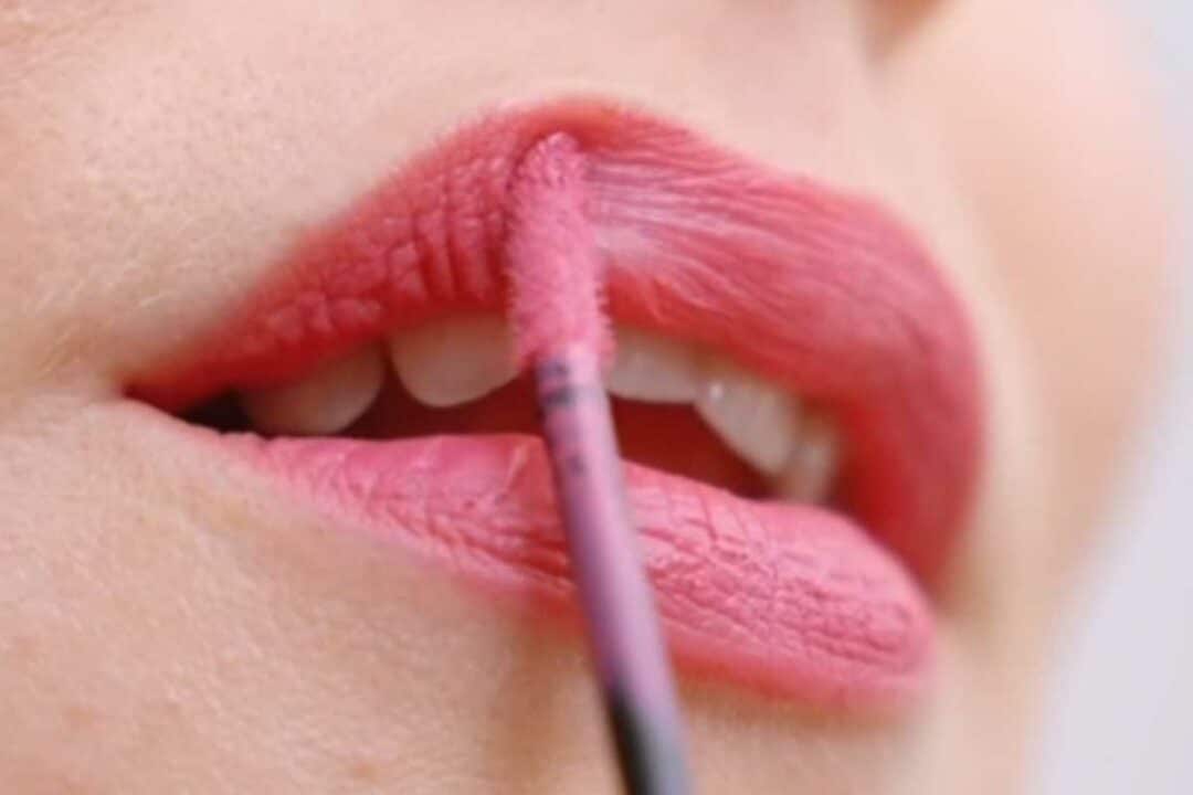 Une femme se remet du rouge à lèvres.