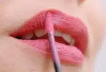 Une femme se remet du rouge à lèvres.