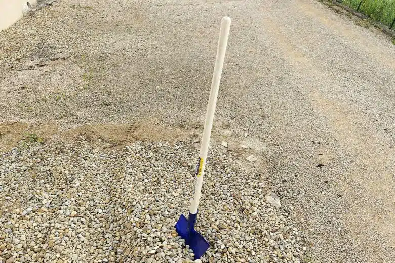 Une pelle plantée dans du gravier.