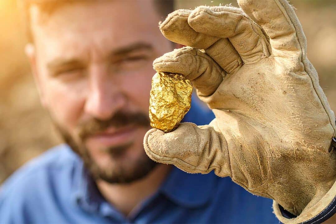 Un homme tient une pépite d'or.