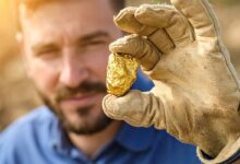 Un homme tient une pépite d'or.