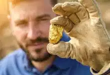 Un homme tient une pépite d'or.