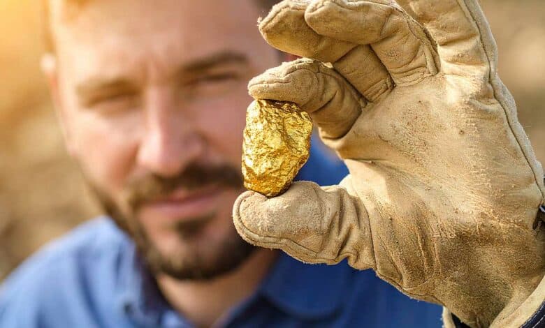 Un homme tient une pépite d'or.