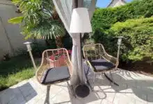 Le lampadaire EZIlight Solar Lamp XL entre deux fauteuils de terrasse, pour des moments lecture ou détente en lumière douce.