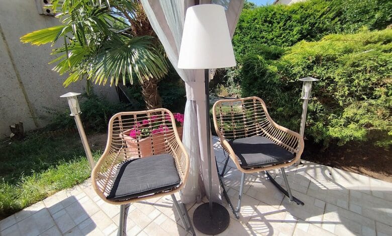 Le lampadaire EZIlight Solar Lamp XL entre deux fauteuils de terrasse, pour des moments lecture ou détente en lumière douce.