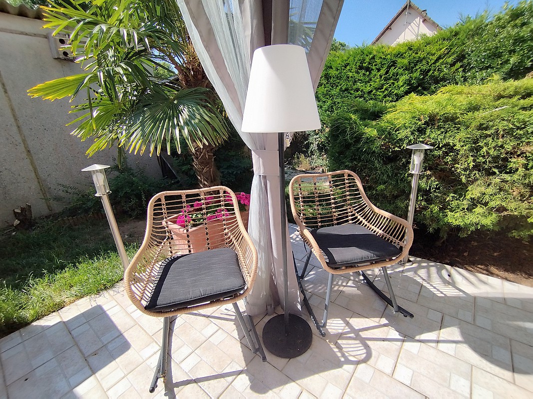 Le lampadaire EZIlight Solar Lamp XL entre deux fauteuils de terrasse, pour des moments lecture ou détente en lumière douce.