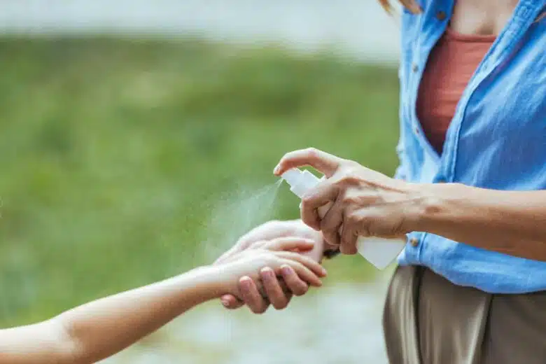 Une mère applique un spray anti moustiques sur le bras de son enfant.