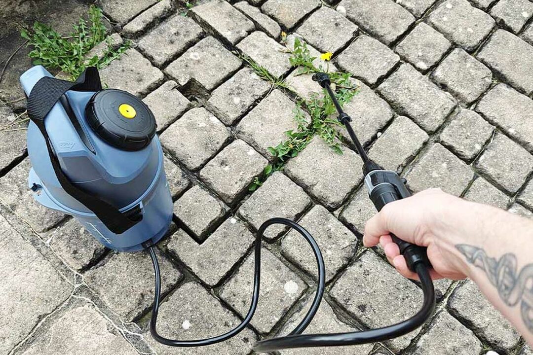 Une personne utilise un pulvérisateur pour désherber.