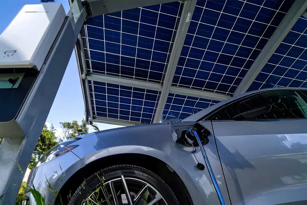 Une voiture électrique garée sous un carport solaire en recharge.
