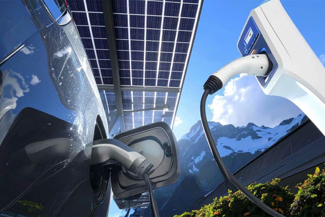 Une voiture électrique recharge sous un carport solaire.