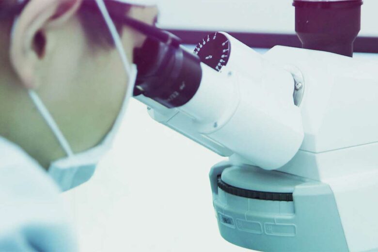 Un scientifique regarde dans un microscope.