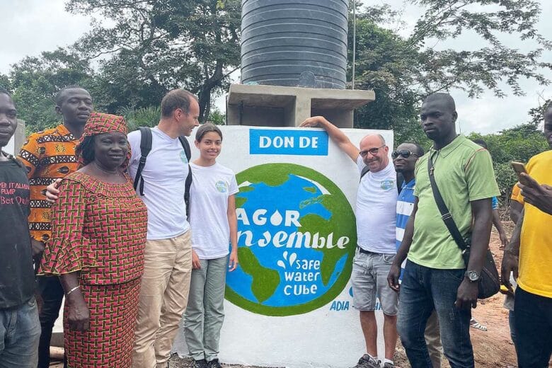 Une équipe de personnes devant une fontaine Safe Water Cube.