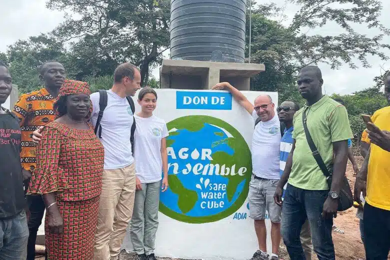 Une équipe de personnes devant une fontaine Safe Water Cube.