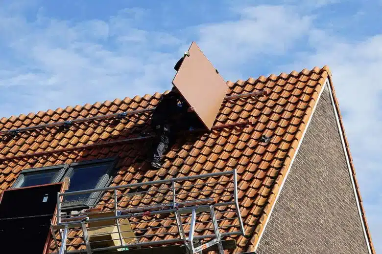 Un homme installe un panneau solaire de couleur terracotta.