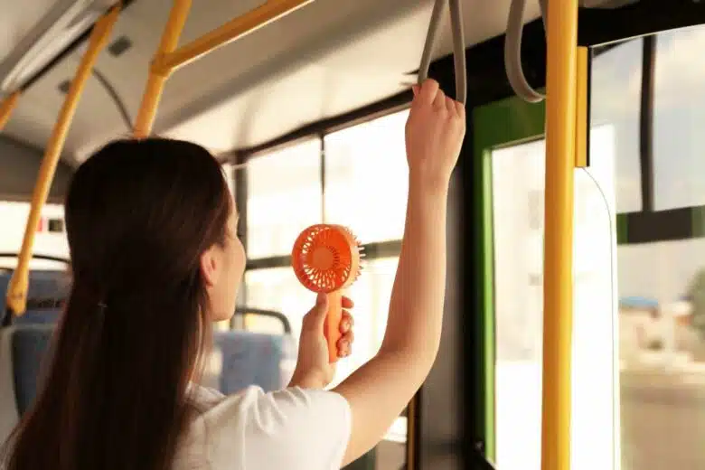 Une femme avec un ventilateur dans les transports en commun.
