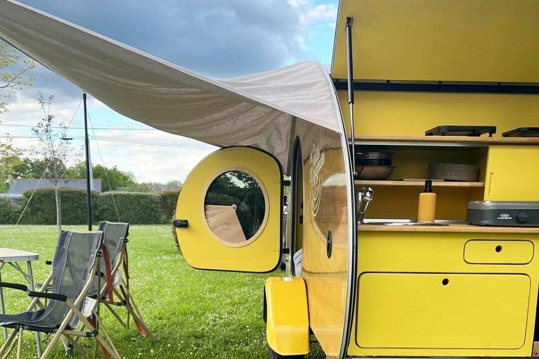 Une mini caravane rétro avec un auvent.
