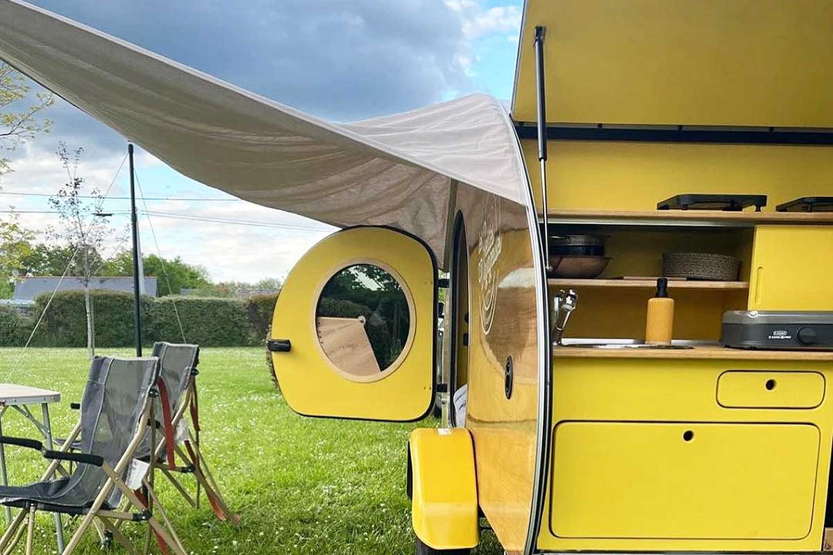Une mini caravane rétro avec un auvent.