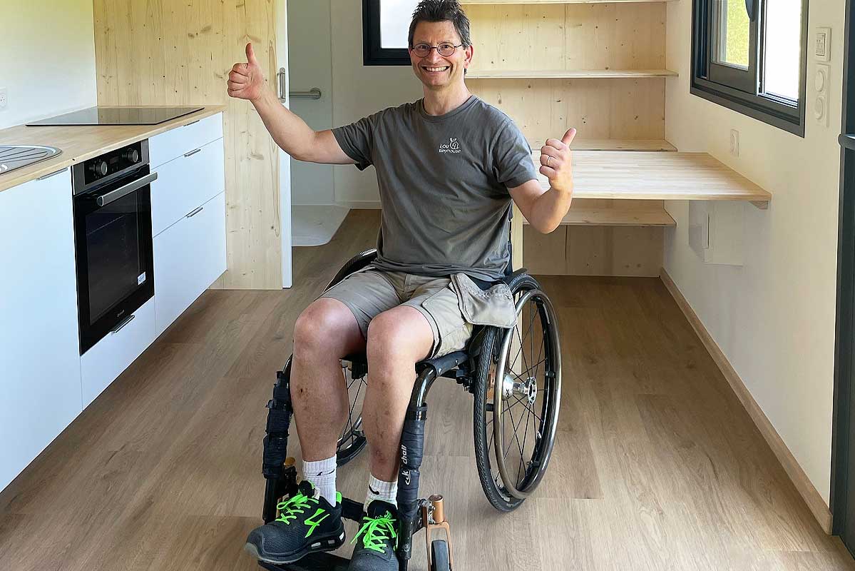 Une personne en fauteuil roulant dans une tiny house.