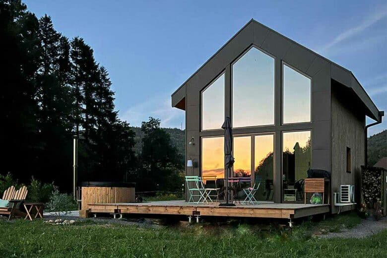 Un coucher de soleil se reflète dans les baies vitrées de la maison.