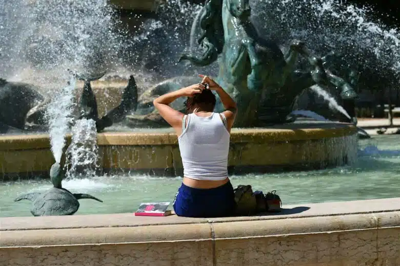Une femme se rafraichit dans une fontaine.