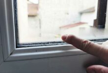 Un doigt constate l'humidité sur une fenêtre.