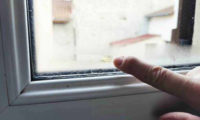 Un doigt constate l'humidité sur une fenêtre.