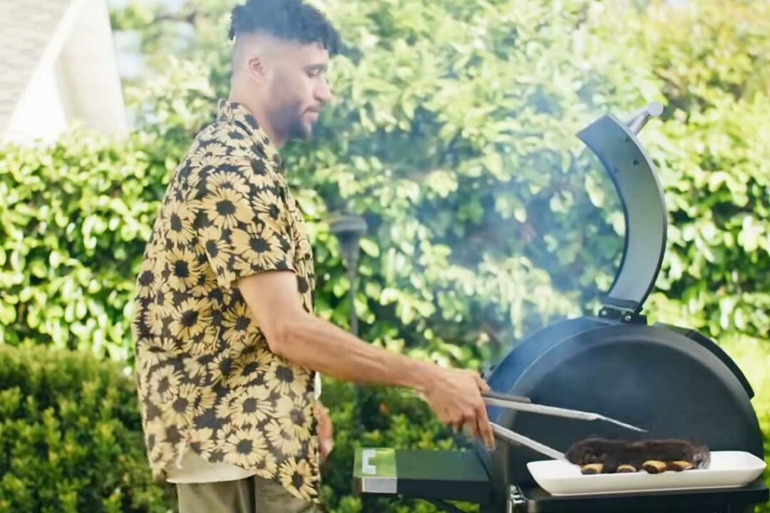 Un homme cuisine au barbecue.