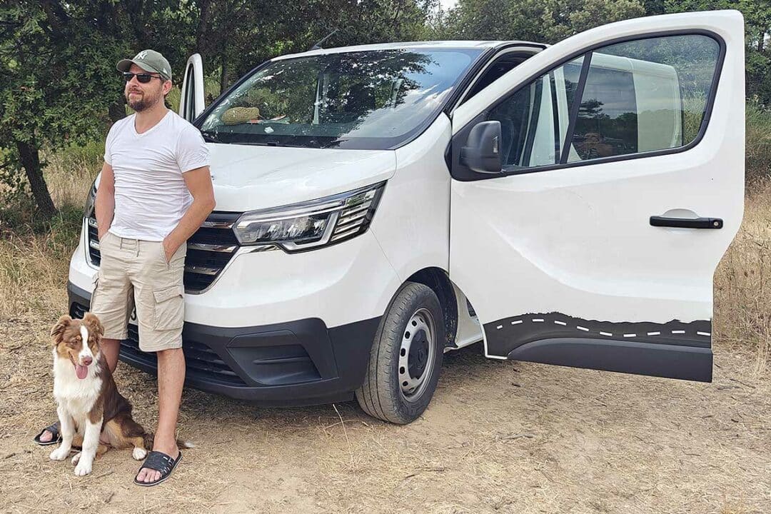 Un homme et son chien devant un van aménagé.