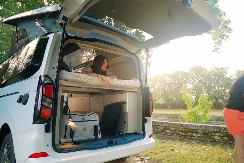 Une femme dans le lit du van aménagé.