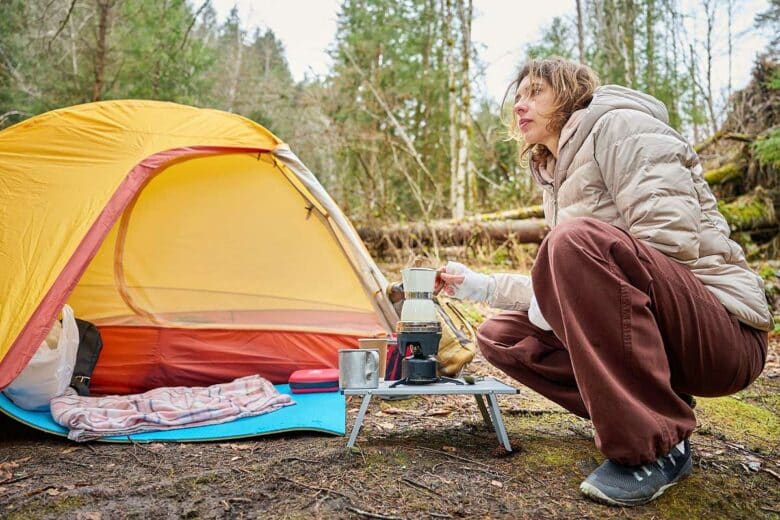 Une femme se fait son café davant sa tente.
