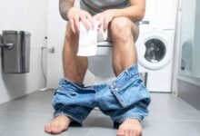 Un homme assis sur des toilettes.