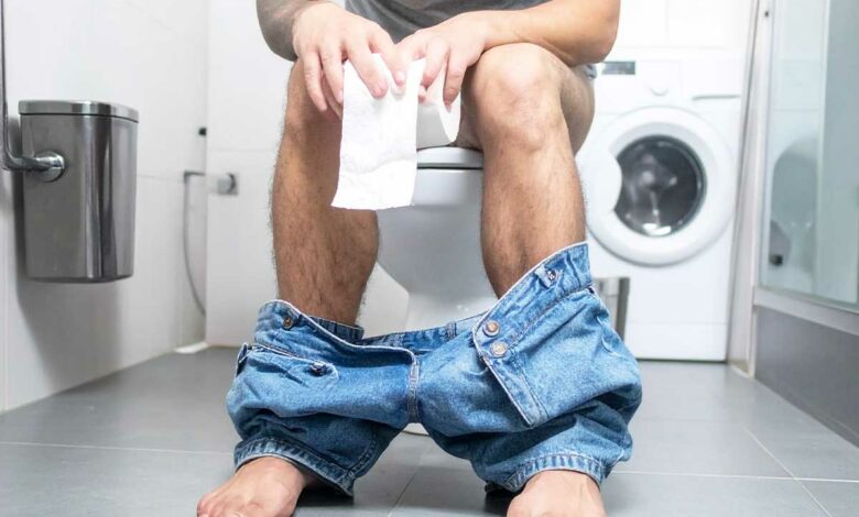 Un homme assis sur des toilettes.