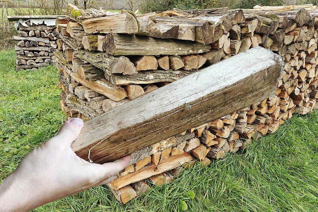 Du bois de chauffage et une buche tenue en main.