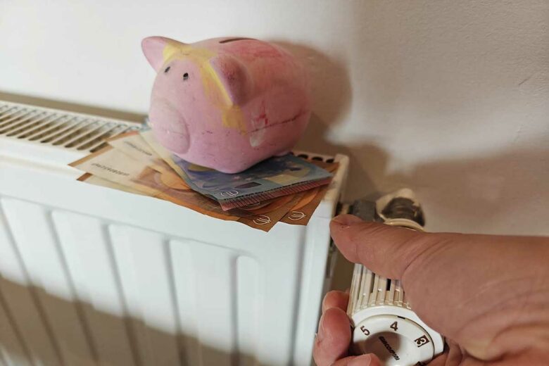 Une personne allume son chauffage avec une tirelire dessus.