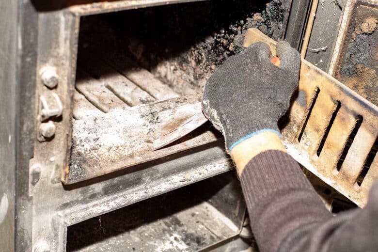 Une personne nettoie un poêle à bois.