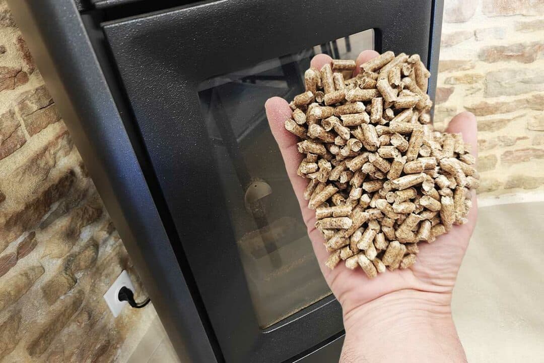 Une poignée de pellets devant un poêle.