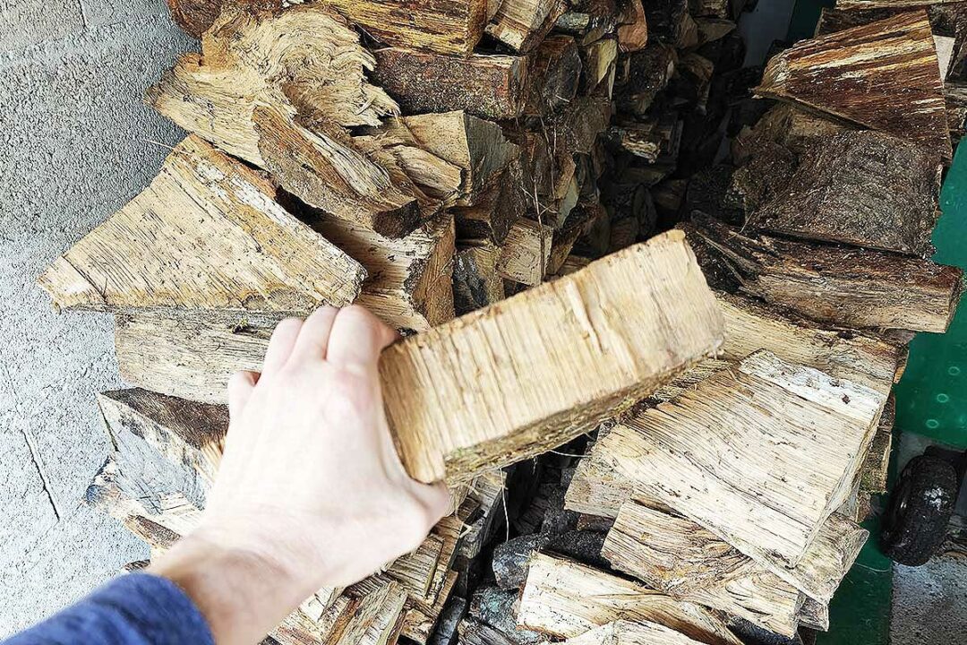 Un tas de bois et une buche tenue en main.