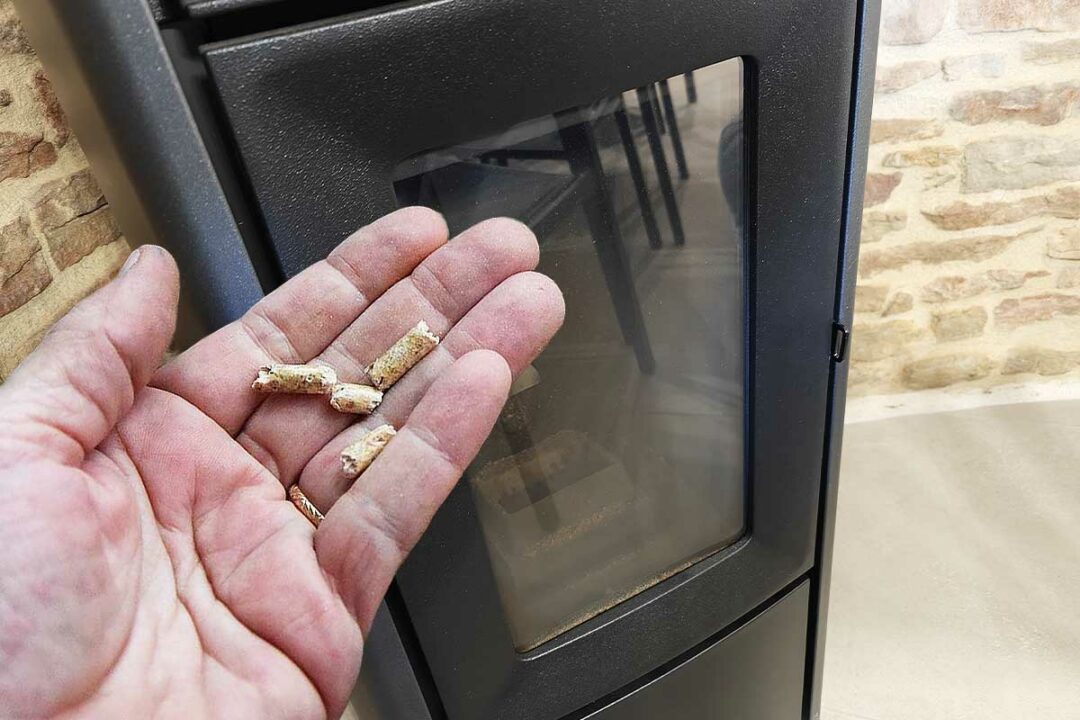 Un poêle à pellet et une main avec des granulés de bois.