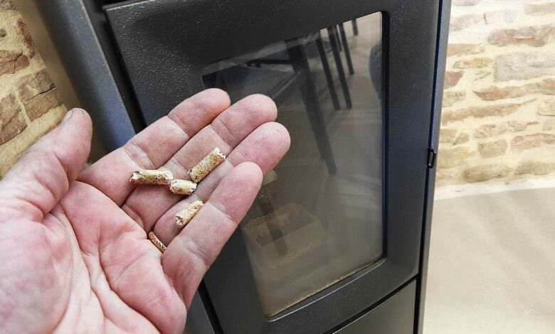 Un poêle à pellet et une main avec des granulés de bois.