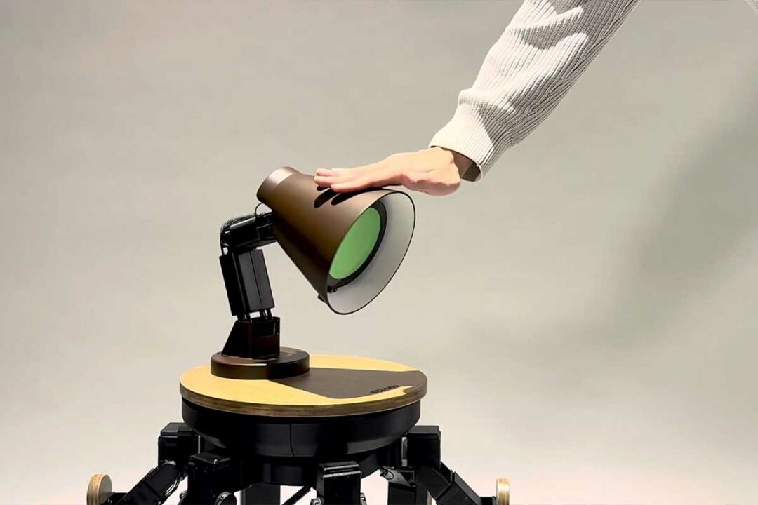 Un homme caresse une lampe robot.