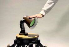 Un homme caresse une lampe robot.