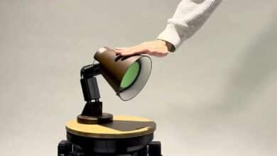 Un homme caresse une lampe robot.