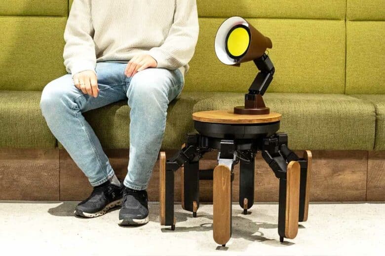 Un homme assis à côté d'une lampe robot.