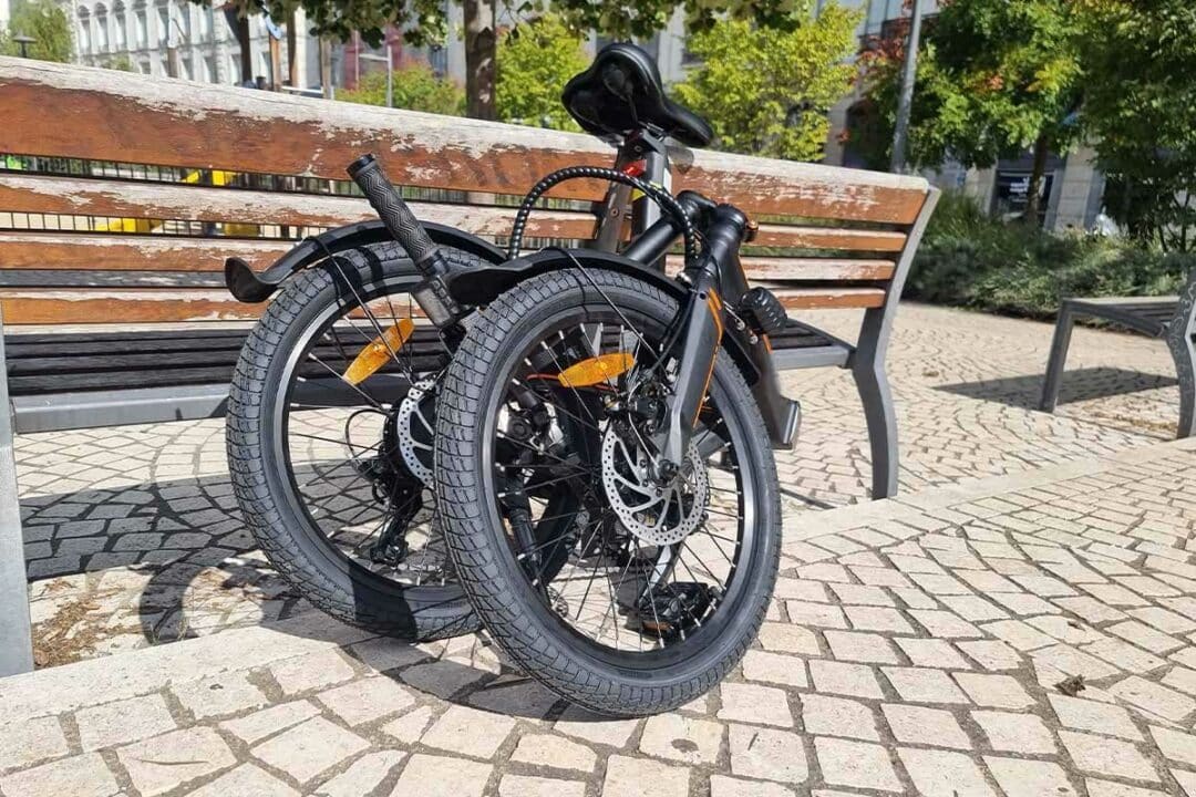 Un vélo pliant contre un banc.