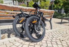 Un vélo pliant contre un banc.