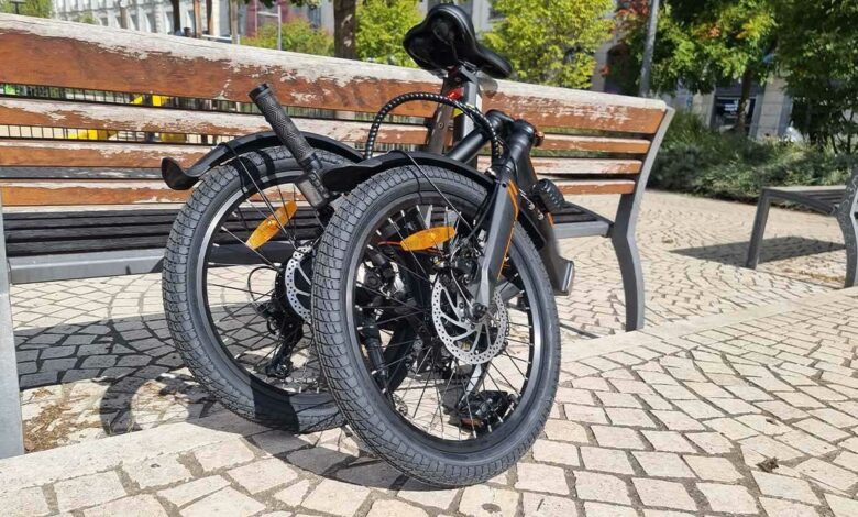 Un vélo pliant contre un banc.