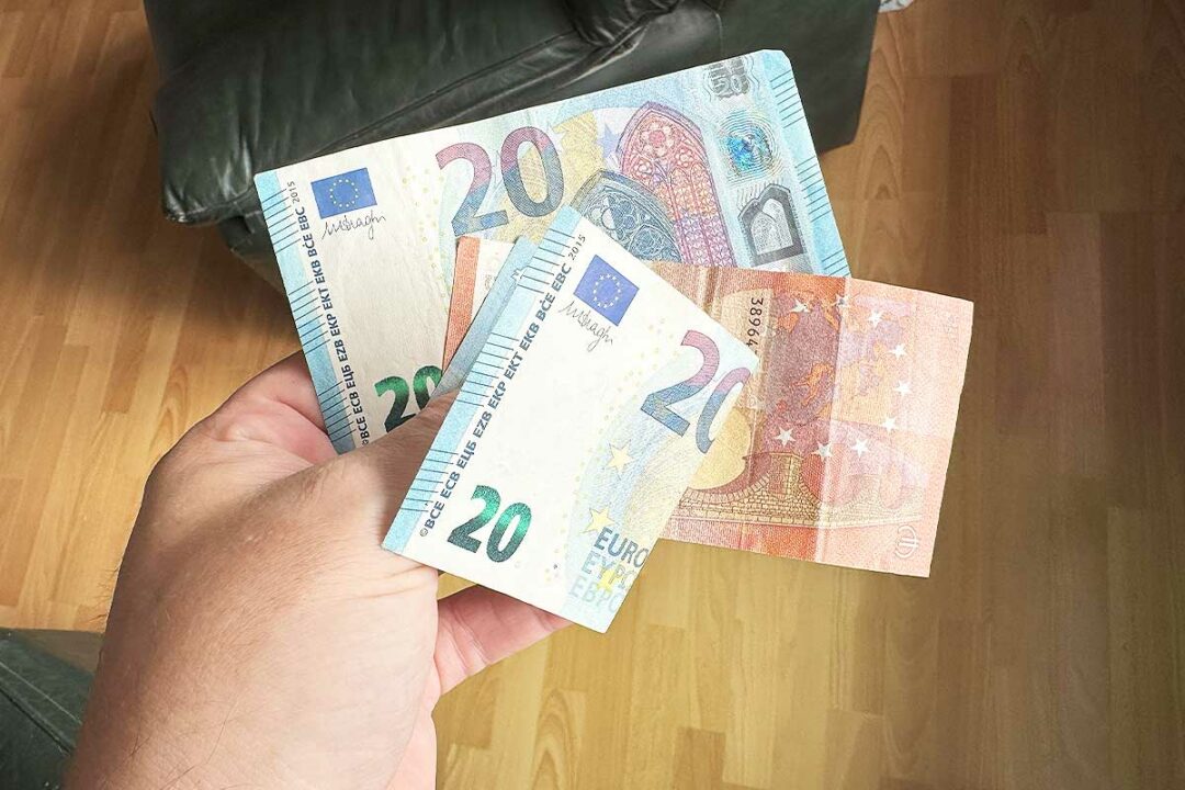 Une personne tient des billets dans la main.