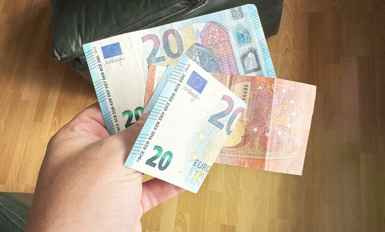 Une personne tient des billets dans la main.