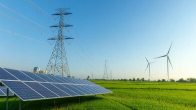 Une étendue avec un pylône électrique, des panneaux solaires et des éoliennes.