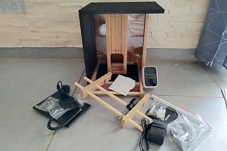 Contenu complet du colis Birdfy : la mangeoire connectée en bambou, la caméra, le panneau solaire et tous les accessoires de fixation.